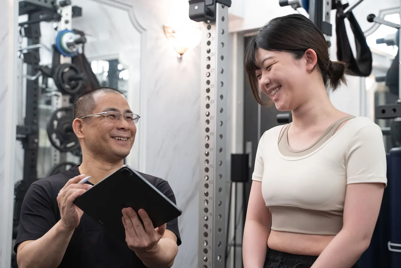 PriGym（プリジム）のトレーナーがタブレットを用いて会員に説明している様子。