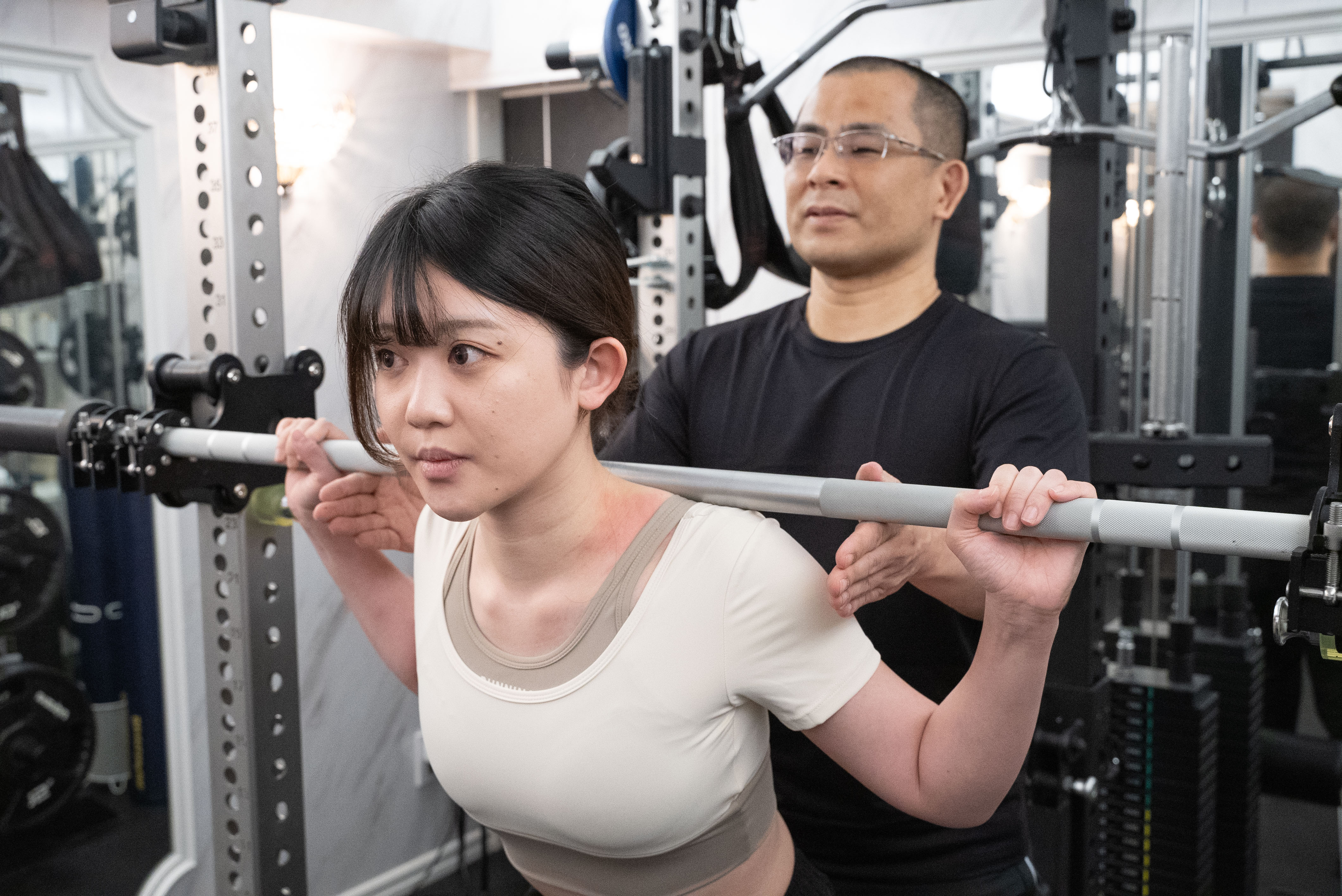 PriGym（プリジム）のセッション風景。集中した表情でスクワットを行う姿を丁寧にサポート。